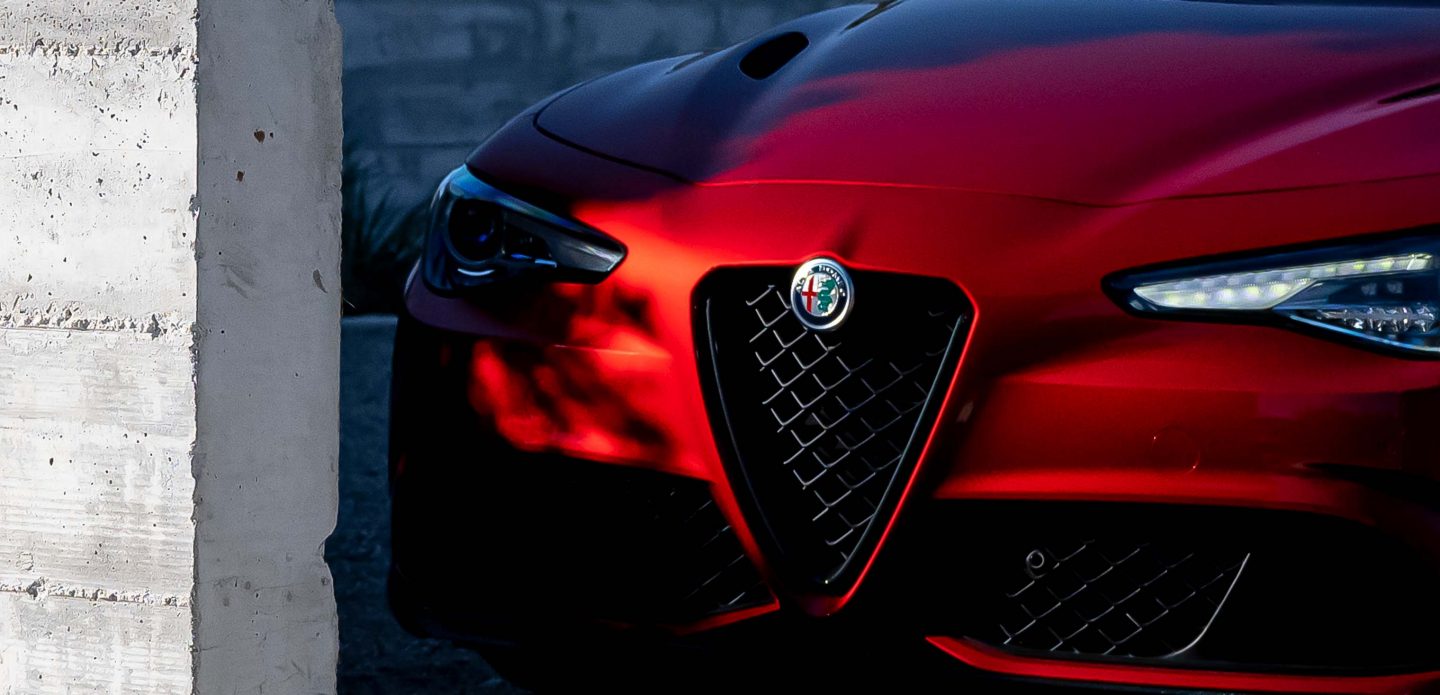 Se muestra la parte delantera de un Alfa Romeo Giulia Quadrifoglio 2023 donde sobresale la parrilla V Scudetto y el emblema de Alfa Romeo.